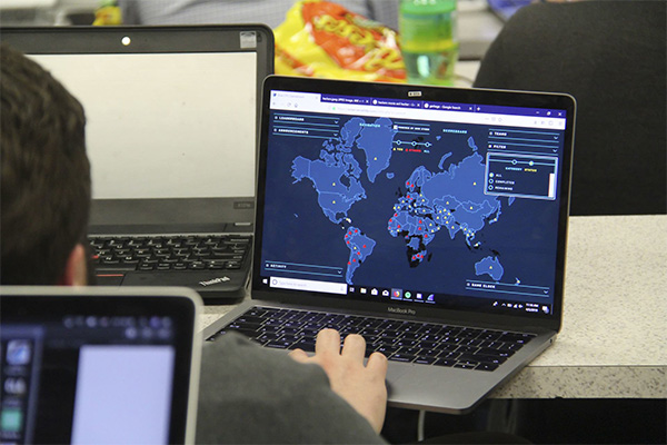 A student working on a laptop with a world map displayed on the screen.