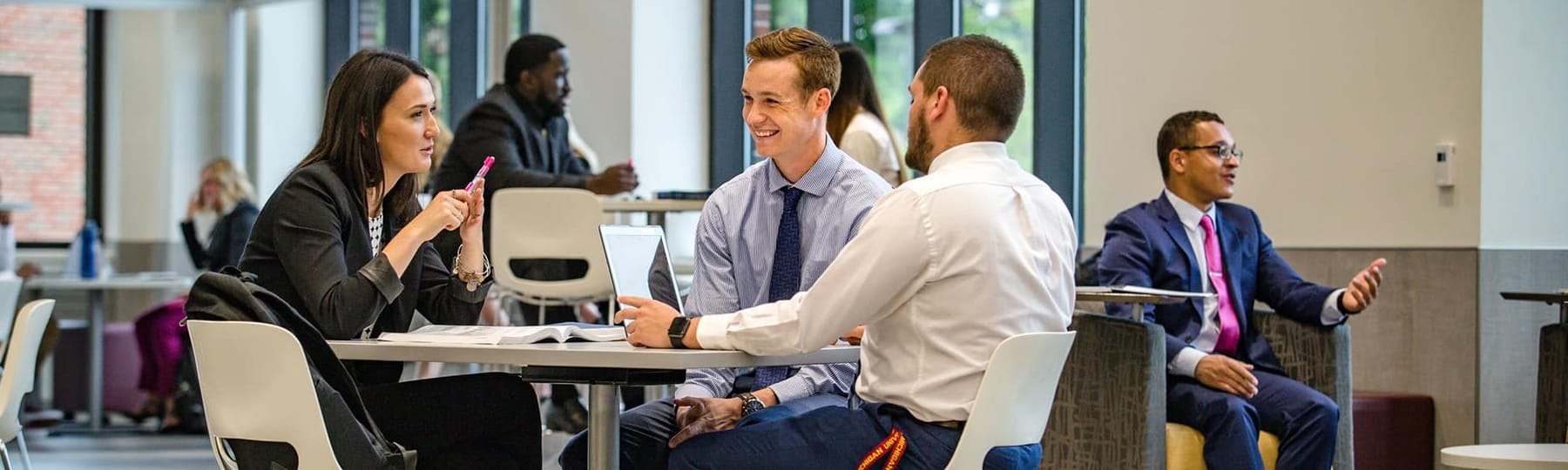 Three business students sit at a table talking in the College of Business Administration.
