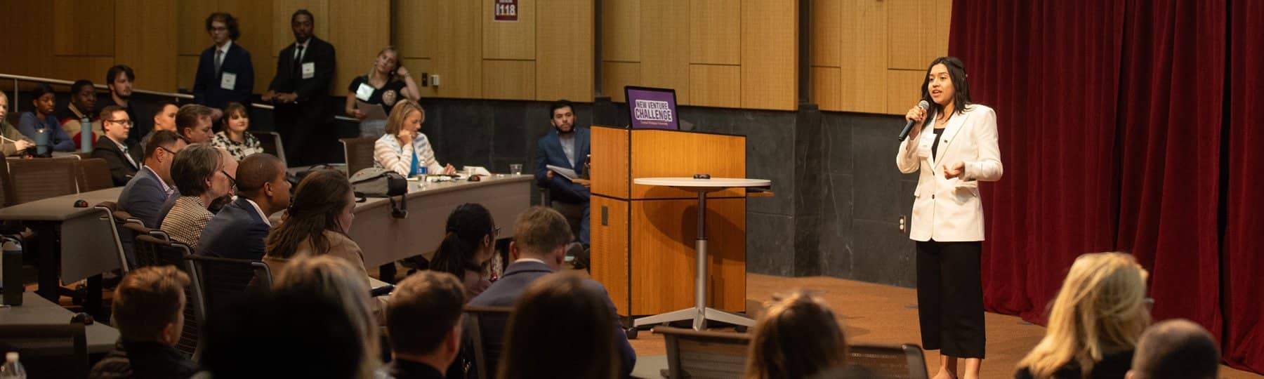 A student standing and speaking in front of a large crowd in French Auditorium.