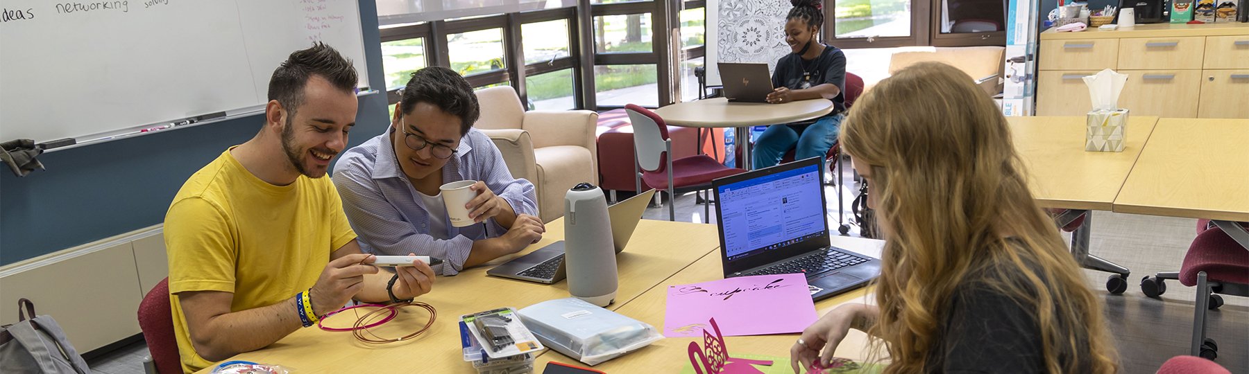 Four students in the Entrepreneurship IDEA Den working on projects.