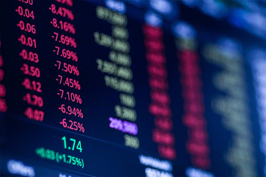 A screen shows gains and losses of the financial markets in green and red text.