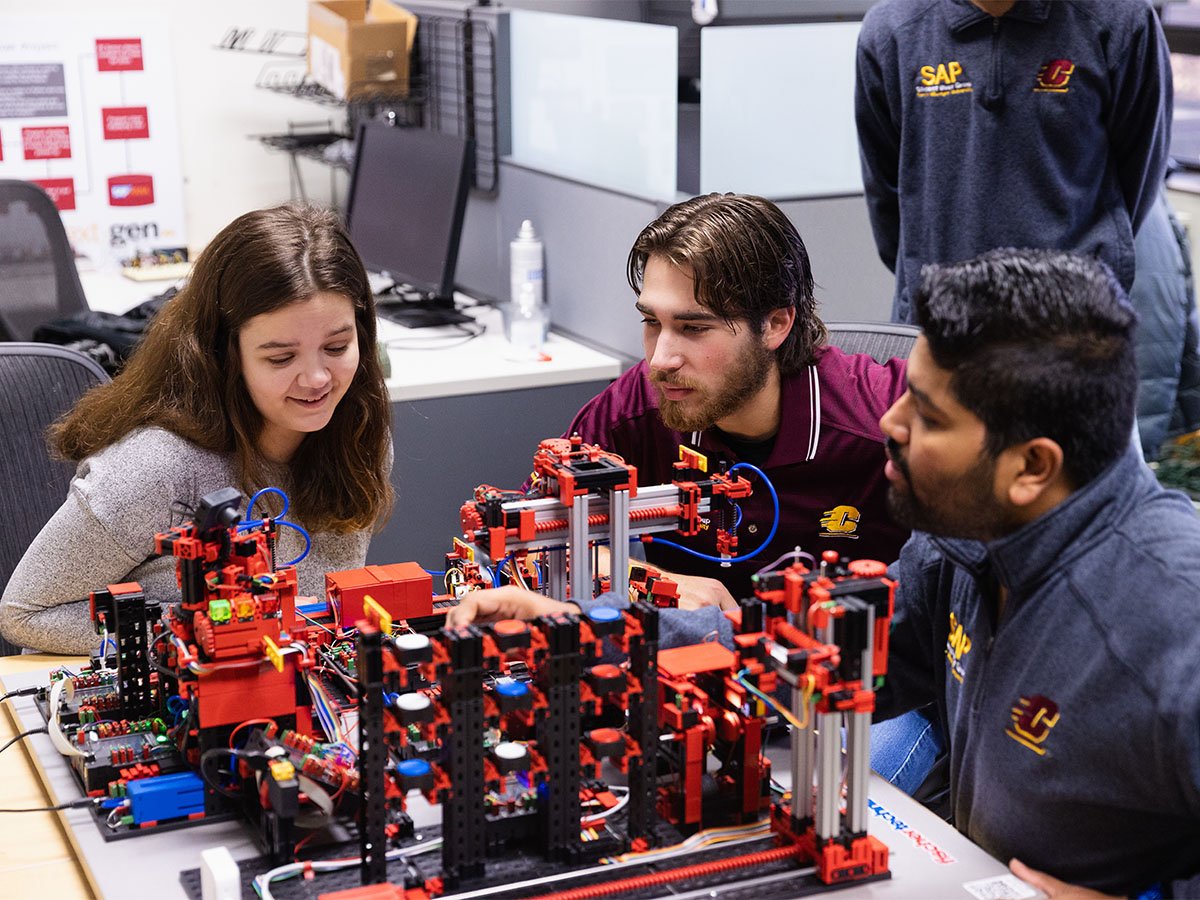 Three students experimenting with a factory model.