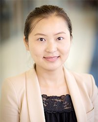 Mohan Song wears a beige blazer and black blouse in a headshot image.