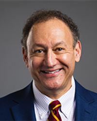 Professor Adam Epstein with brown hair, blue suit, and maroon and gold tie.