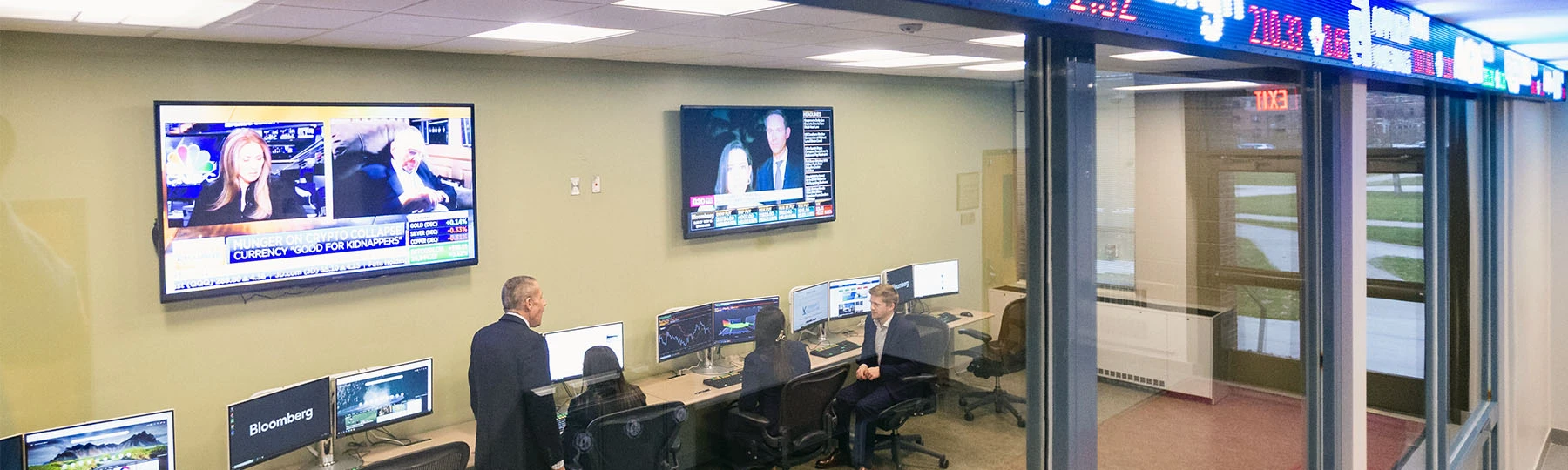 A group of people sitting at desks with computers inside Central Michigan Universities College of Business Administration building.