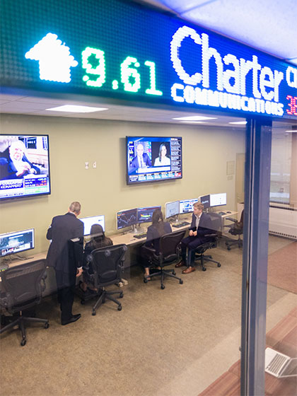 A group of people sitting at desks with computers inside Central Michigan Universities College of Business Administration building.