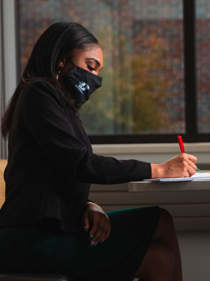 A student in business attire taking notes.