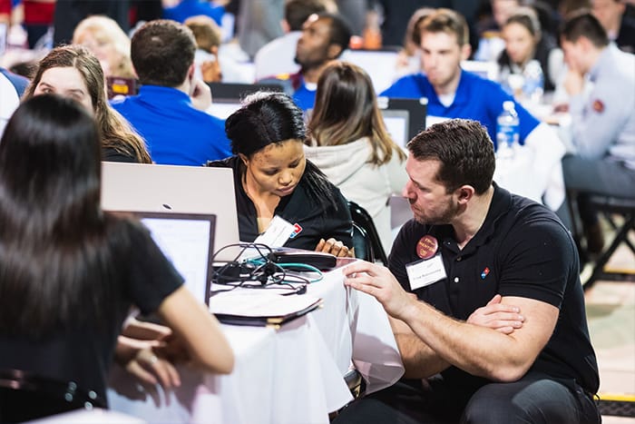 A mentor talks with a student during the ERPsim competition.