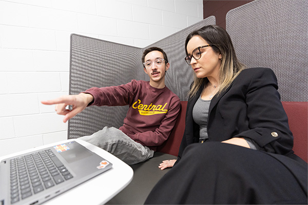 A student showing a professor something on his laptop.