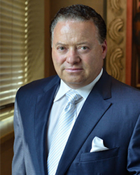 Celani_Portrait_200x250 A man wearing a blue blazer, white shirt and tie.