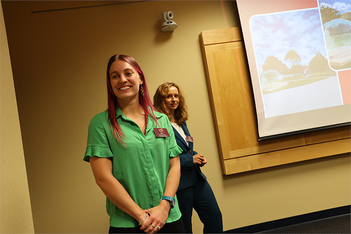 Two women smiling in front of a screen