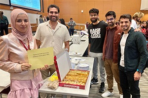 Group of Arab American students standing around a table smiling at 2022 Get Involved Fair.