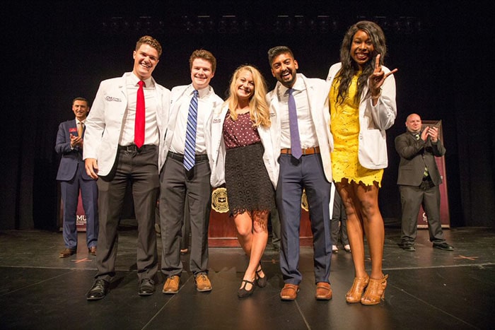 20210921_white_coat_group_700x467 A group of students wearing white lab coats stand together and smile at a white coat ceremony.