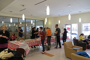 A group of student gather around a table with a heart table cloth and converse over Valentine's treats.