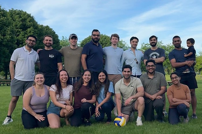 A group of people posing outside with a soccer ball.