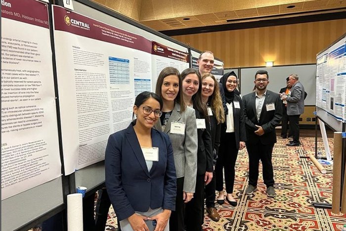 A group of residents pose in front of a poster presentation.