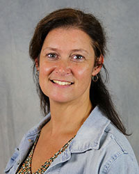 Headshot of Donelle Kiessel wearing a light blue jean jacket and multi-colored shirt.