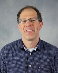 Headshot of Shai Brosh wearing a blue shirt and glasses.