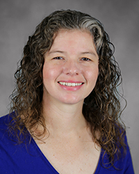 A professional headshot of Katherine Battisti in dark blue attire against a gray background.
