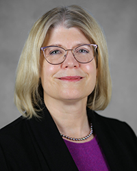 A professional headshot of Wendy Biggs in dark attire against a gray background.