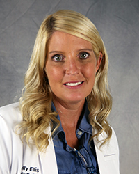 a woman with blonde hair wearing a white medical jacket and standing before a gray background