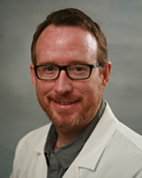 A professional headshot of Steve McLean in gray and white attire against a gray background.
