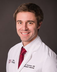 A professional headshot of Benjamin Schoener in white attire against a dark gray background.