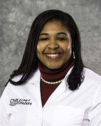 A woman with long, black hair and a maroon blouse wears a white coat and smiles for a headshot.