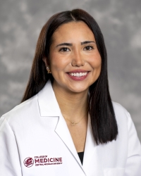 Devlin, Victoria_student_200x250 A smiling person with long dark hair wearing a white medical coat with