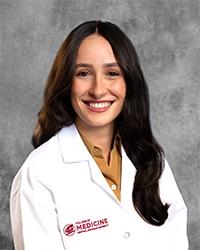A female CMU College of Medicine medical student wearing her white coat as she smiles for the camera.