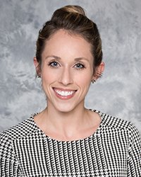 A professional headshot of Olivia Bolen in black and white attire against a gray background.