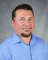 A professional headshot of Michael Cannova in light blue attire against a gray background.