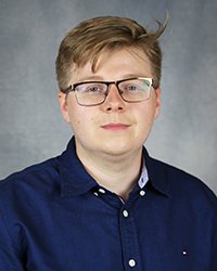 A professional headshot of Michal Dusza in dark blue attire against a gray background.