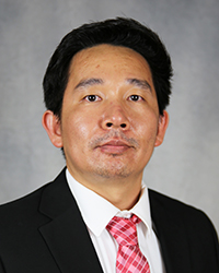 A professional headshot of Cuong La in dark attire against a gray background.