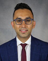 A professional headshot of Mohammed Saiyed in dark blue attire against a gray background.