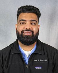 Headshot of Viraj Sidhu wearing a black jacket over blue shirt.