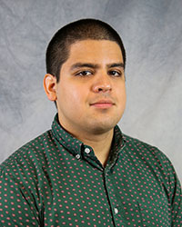 Headshot of Michael Gomez wearing a green dress shirt with a red dotted pattern.
