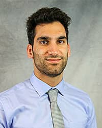 Headshot of Sheikh Ajaz wearing a blue dress shirt and a gray patterned necktie.