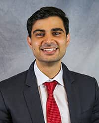 Headshot of Wasef Al-Khateeb wearing a dark gray suit with a white dress shirt and a red necktie.