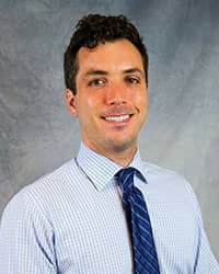 Headshot of Robert Kasemodel white dress shirt with blue checkered pattern and a dark blue tie with light blue stripes.