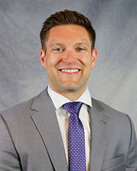 Headshot of William Starbird wearing a grey suit.