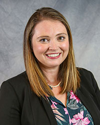 Headshot of Laina Weinman wearing a black blazer and a floral print blouse.