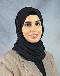 Batool Al-Qanber wears a tan sport jacket with black colored hijab covering around head and neck.