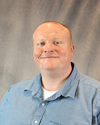 Headshot of Christopher Hesterly wearing a blue button up shirt.