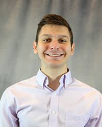 Headshot of Bradley Miller wearing a purple button up shirt.