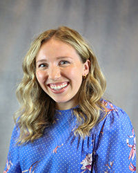 Headshot of Riva Morin wearing a blue patterned top.