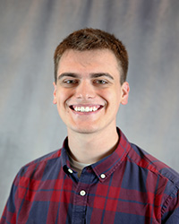 Headshot for Dillon Nerland wearing a blue and red plaid button up shirt.