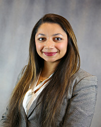 Headshot of Herchran Singh wearing a grey blazer and a white top.