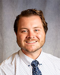 Eudis, Brennon Brennon Eudis is wearing a white polka dot shirt and blue patterned tie.
