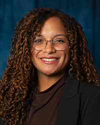 Patterson, Santanna a woman with curly hair wearing glasses